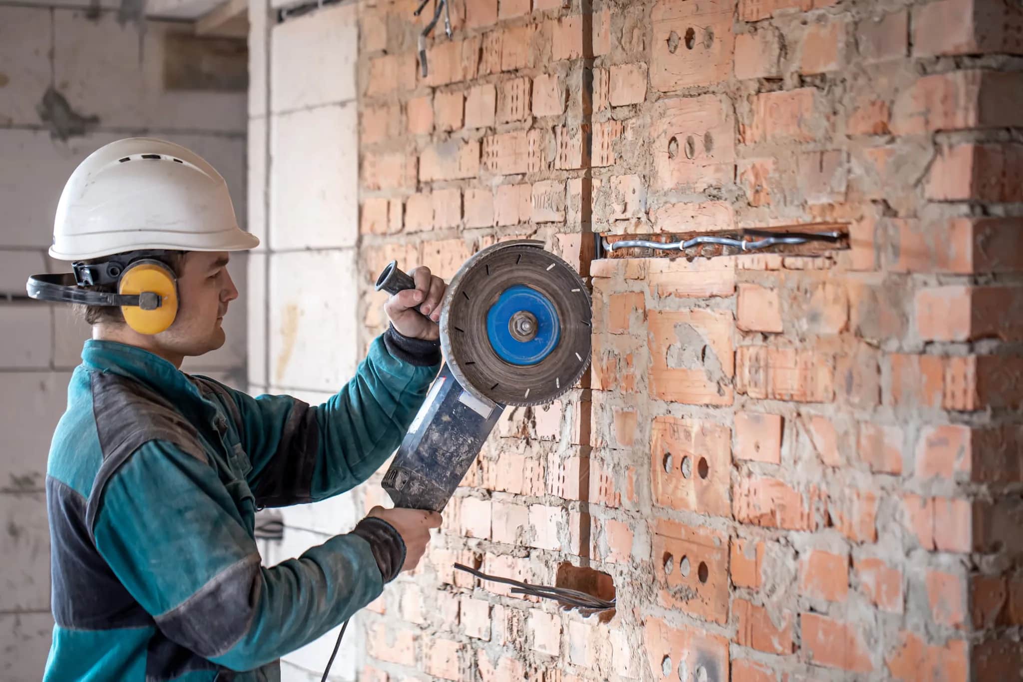 A builder cutting into a brick wall during a renovation