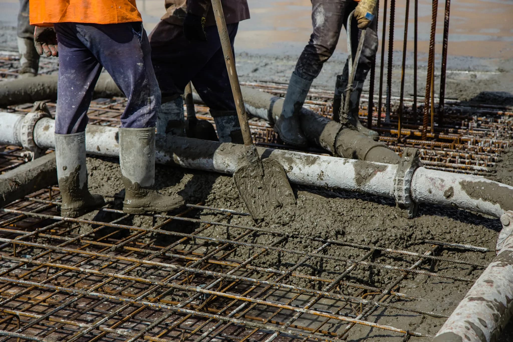 Wet concrete being poured over a reinforced steel grid