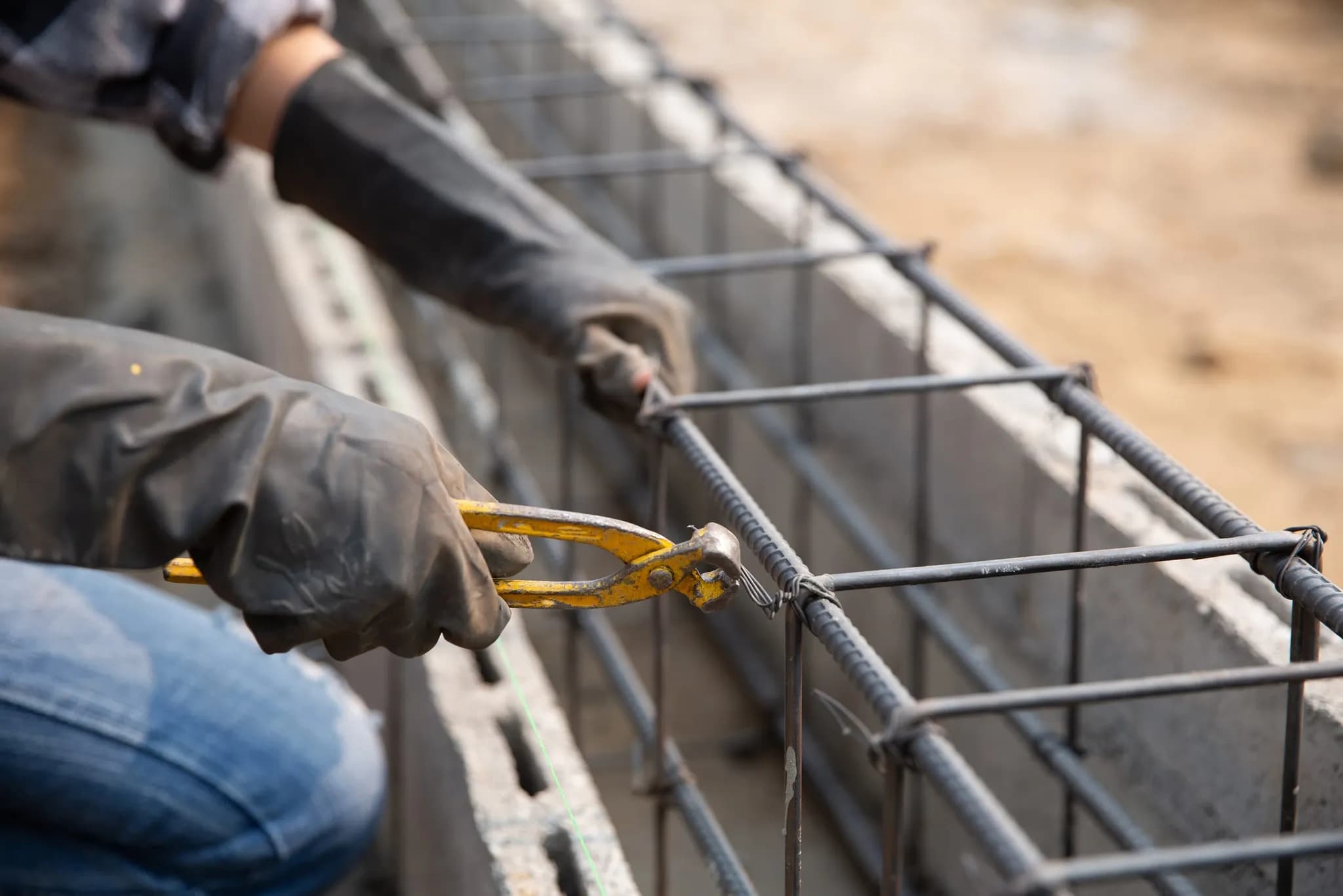 Close-up of gloved hands bending reinforcement bar on a construction site
