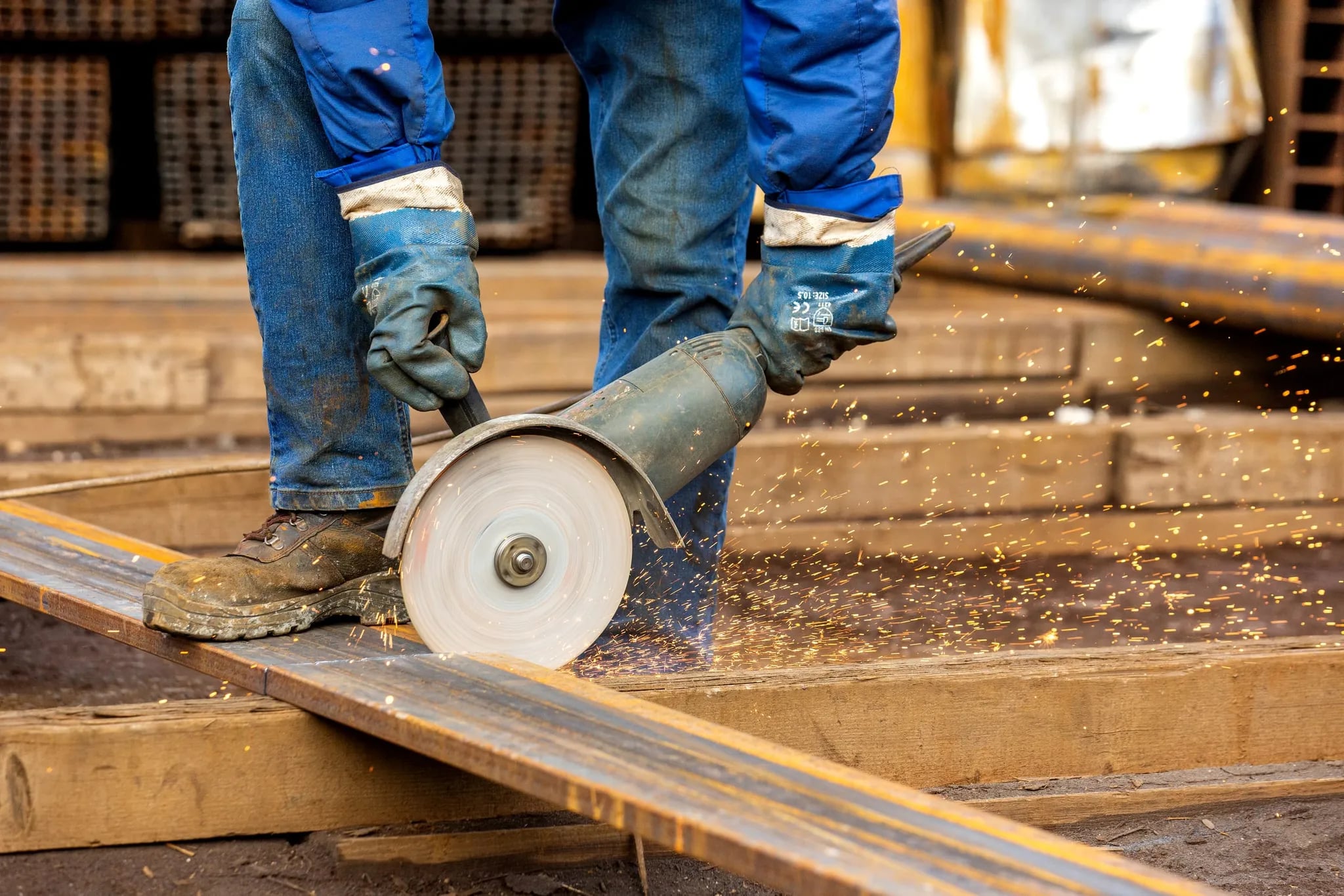A worker cutting a steel plate with an angle grinder, sparks flying