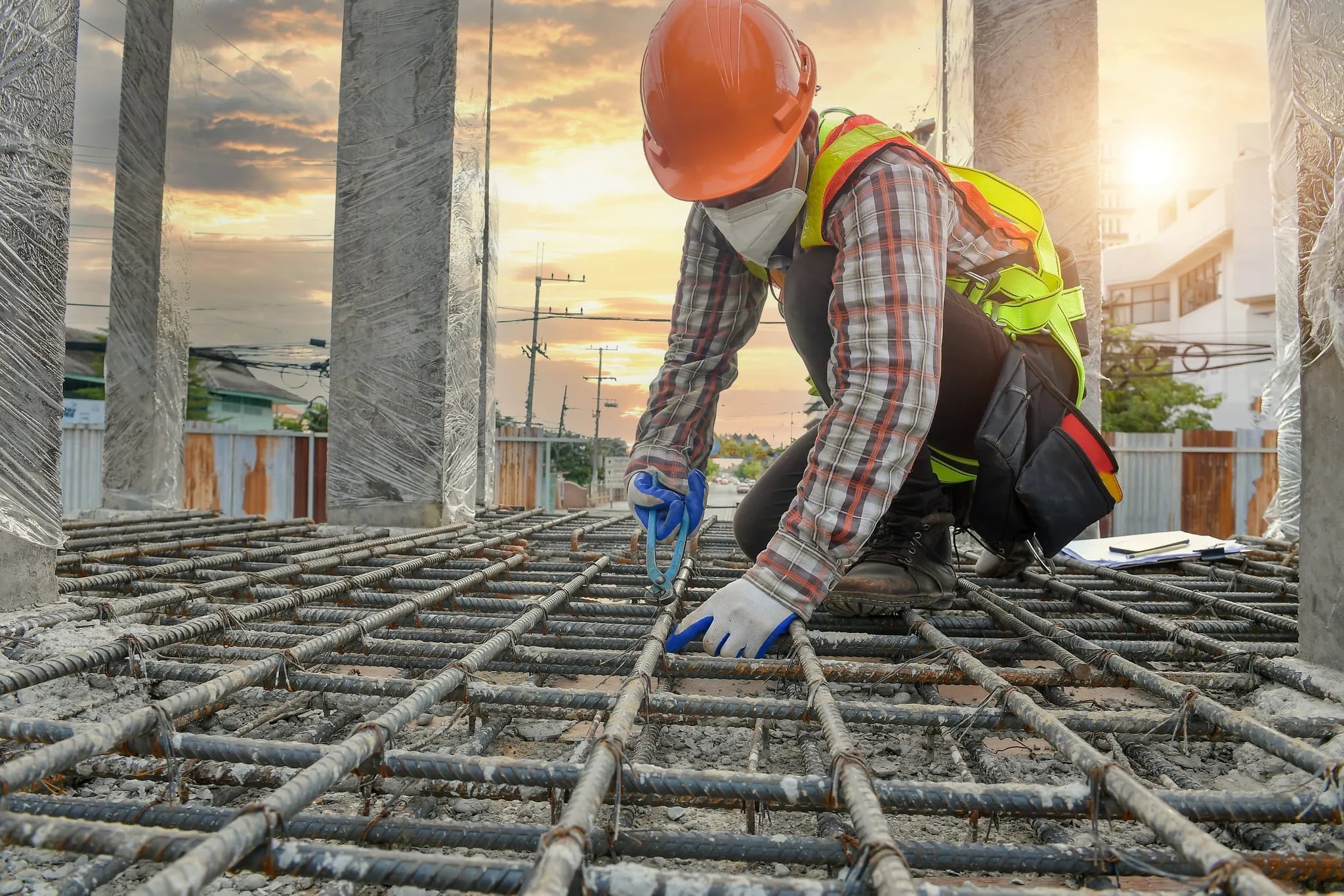 A worker tying reinforcement steel for a foundation at golden hour