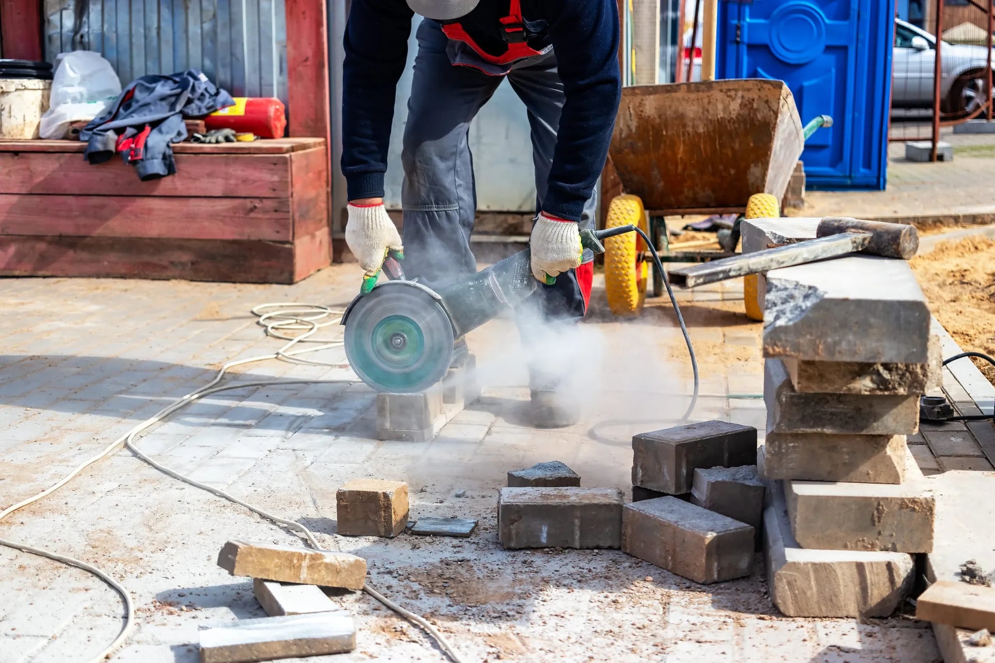 A worker cutting paving slabs with a diamond-blade grinder