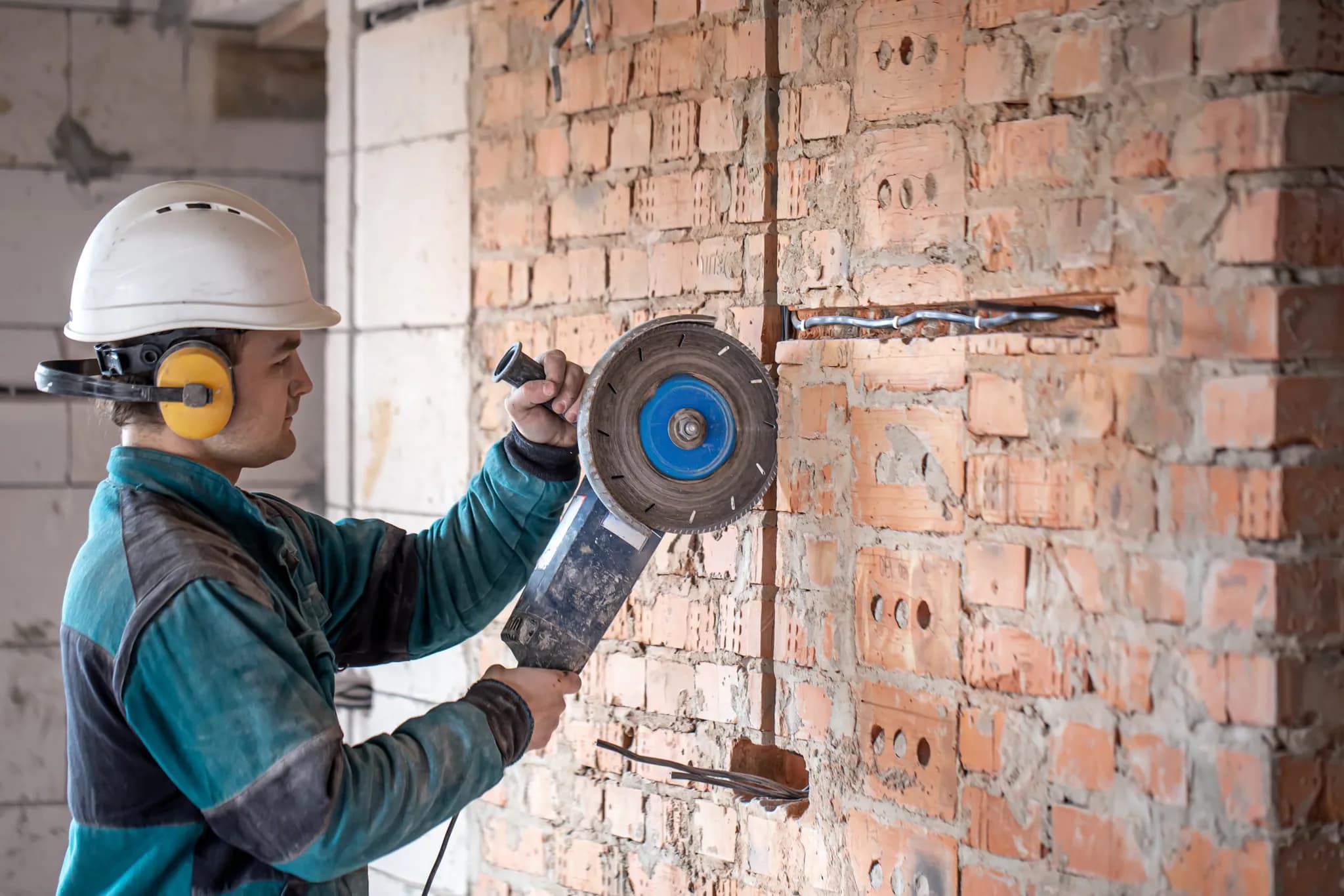 A builder cutting into a brick wall during a renovation